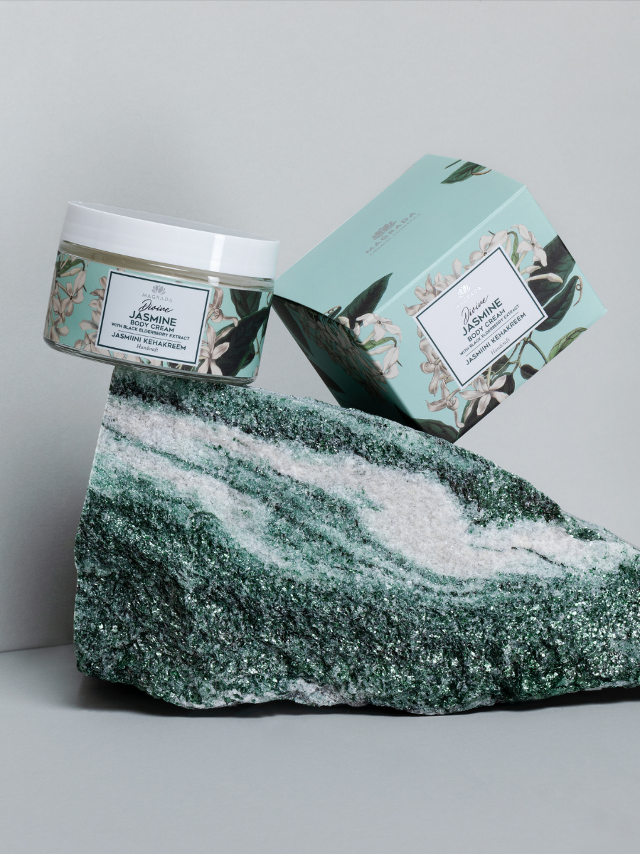 Magrada Organic Cosmetics black elderberry extract lotion in floral jar and box displayed on green textured stone