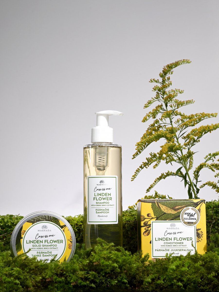 Magrada Organic Cosmetics Linden Flower Shampoo in clear pump bottle with solid shampoo and conditioner surrounded by green foliage