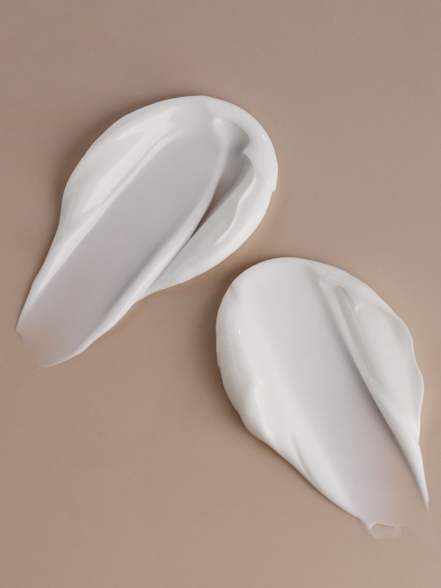 Smooth white cream texture of Magrada moisturizing balm on a beige background