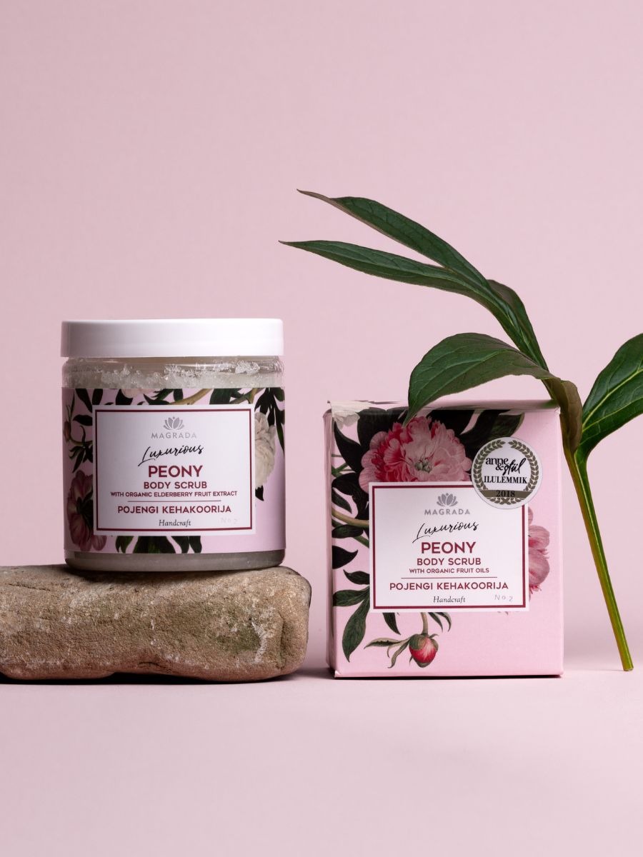 Magrada Organic Cosmetics organic peony body scrub jar and pink box with floral design and green leaves on stone