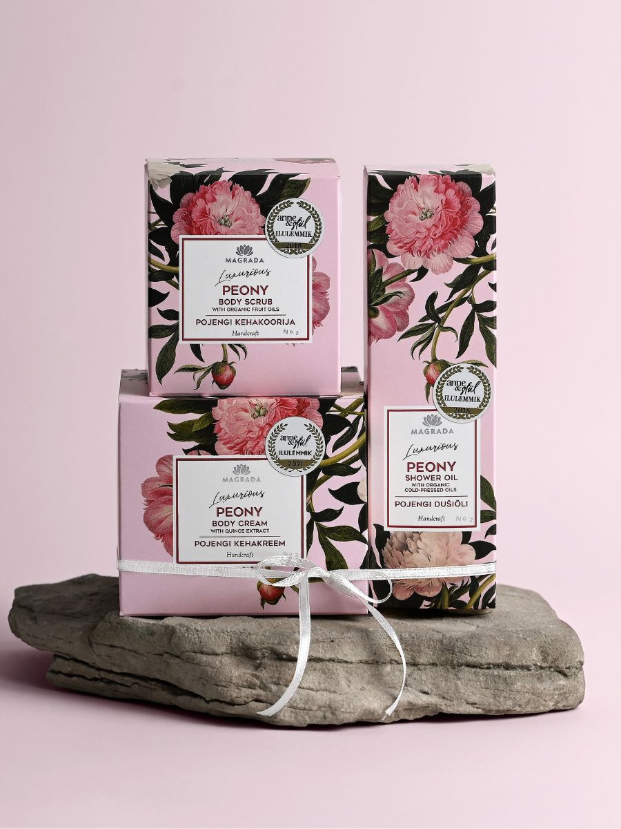 Magrada Organic Cosmetics organic peony body scrub and skincare products in pink floral packaging on stone display