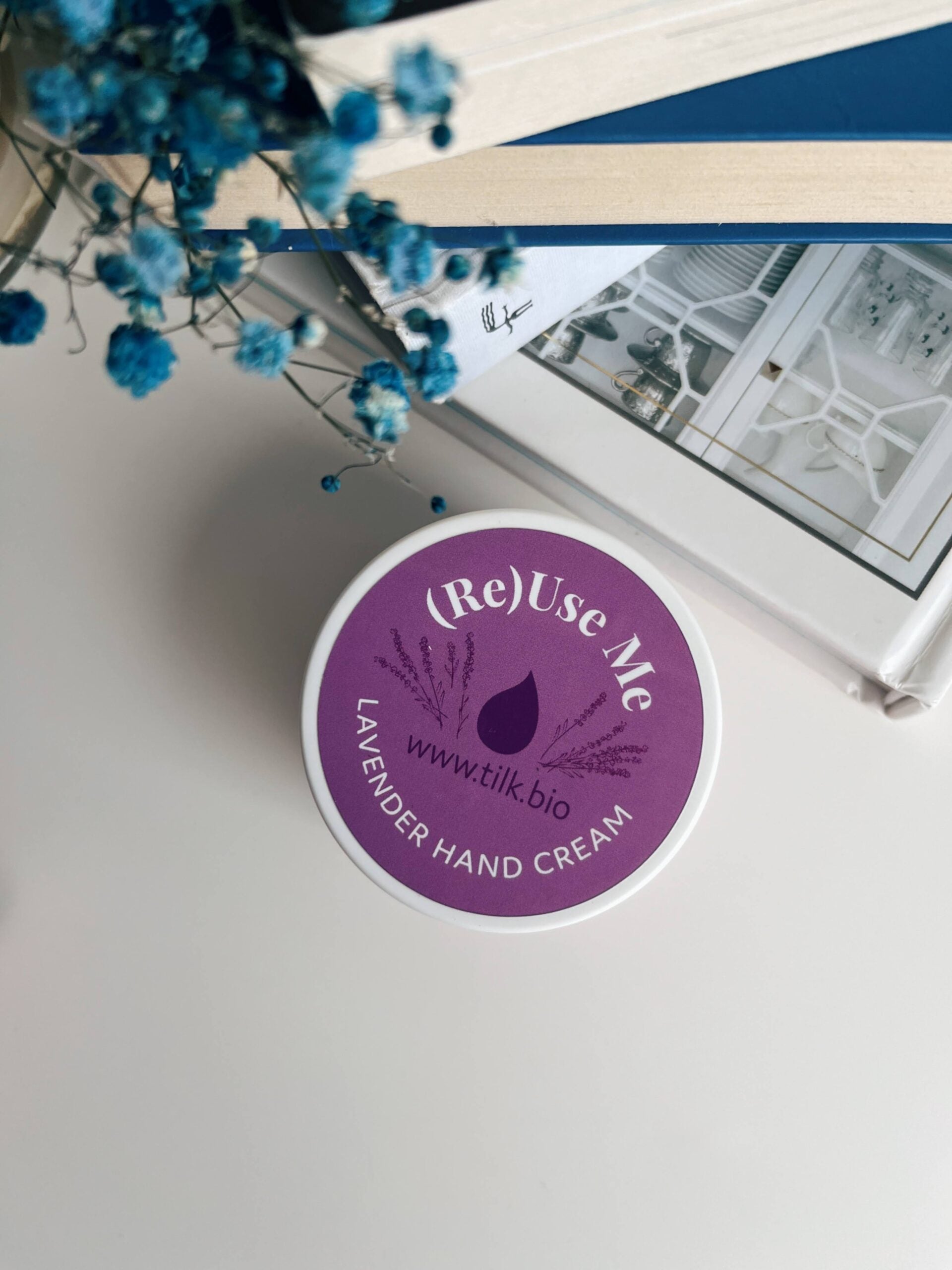 Tilk lavender hand cream 50ml container with purple label on white surface next to books and blue flowers
