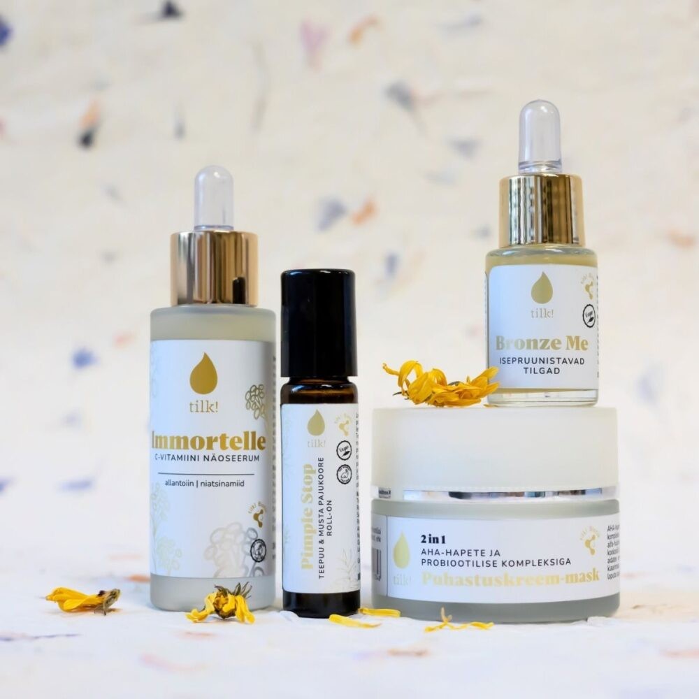 Tilk self-tanning drops with hyaluronic acid bottles and skincare products with dropper caps on white surface