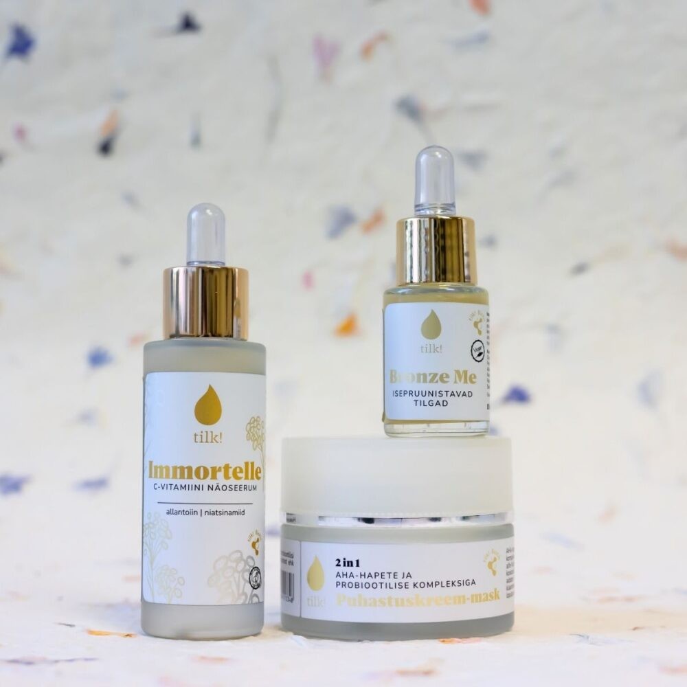 Tilk self-tanning drops with hyaluronic acid in dropper bottle alongside skincare jars on a white surface