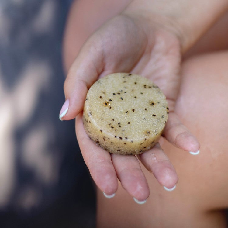 Vegan Fox kiwi seed body scrub round bar with visible seeds held in hand for exfoliation